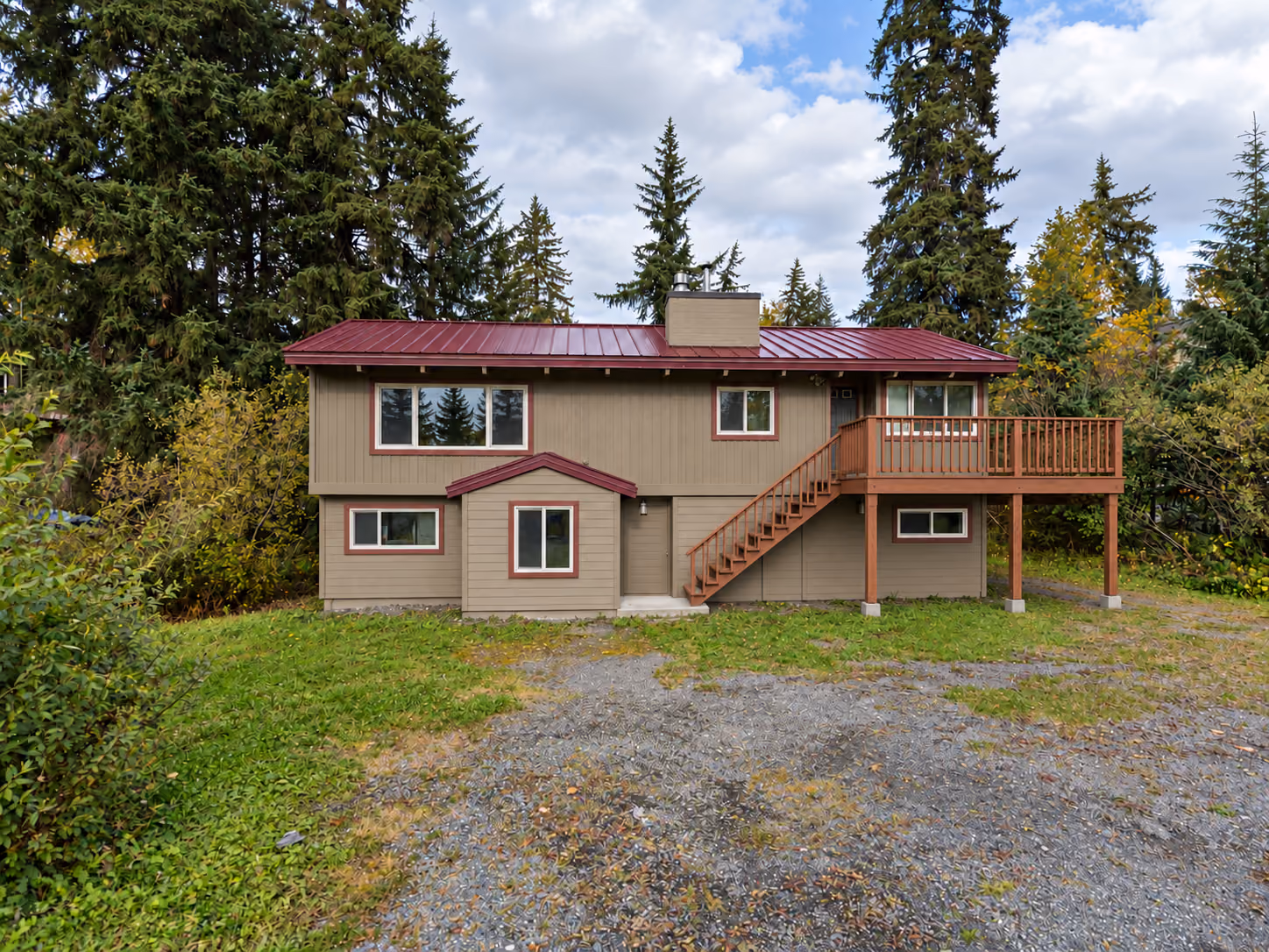 Girdwood split-level home with a red standing seam metal roof and side deck