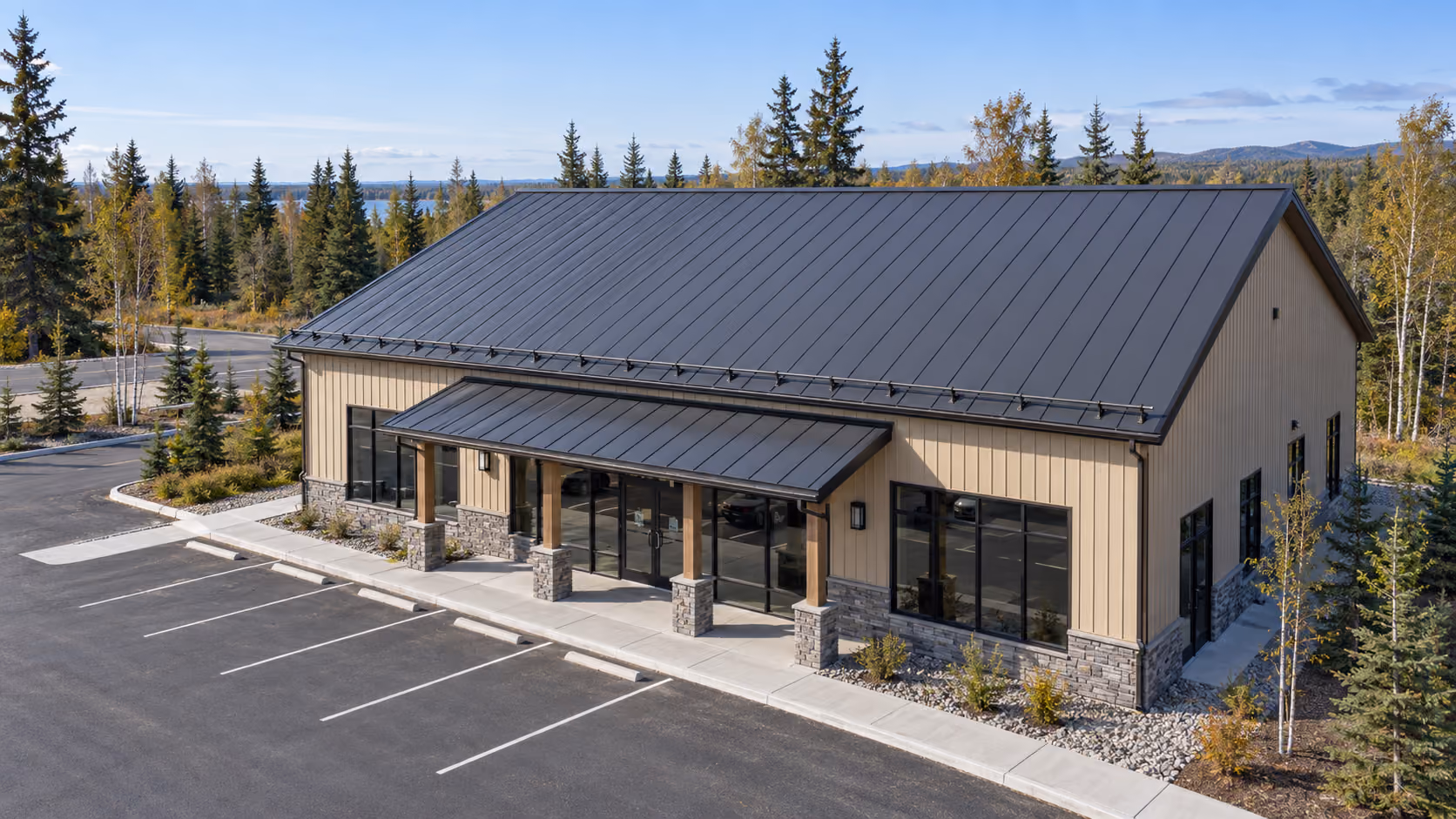Commercial building with a dark standing seam metal roof, snow guards, and a metal entry canopy, fall trees around the lot