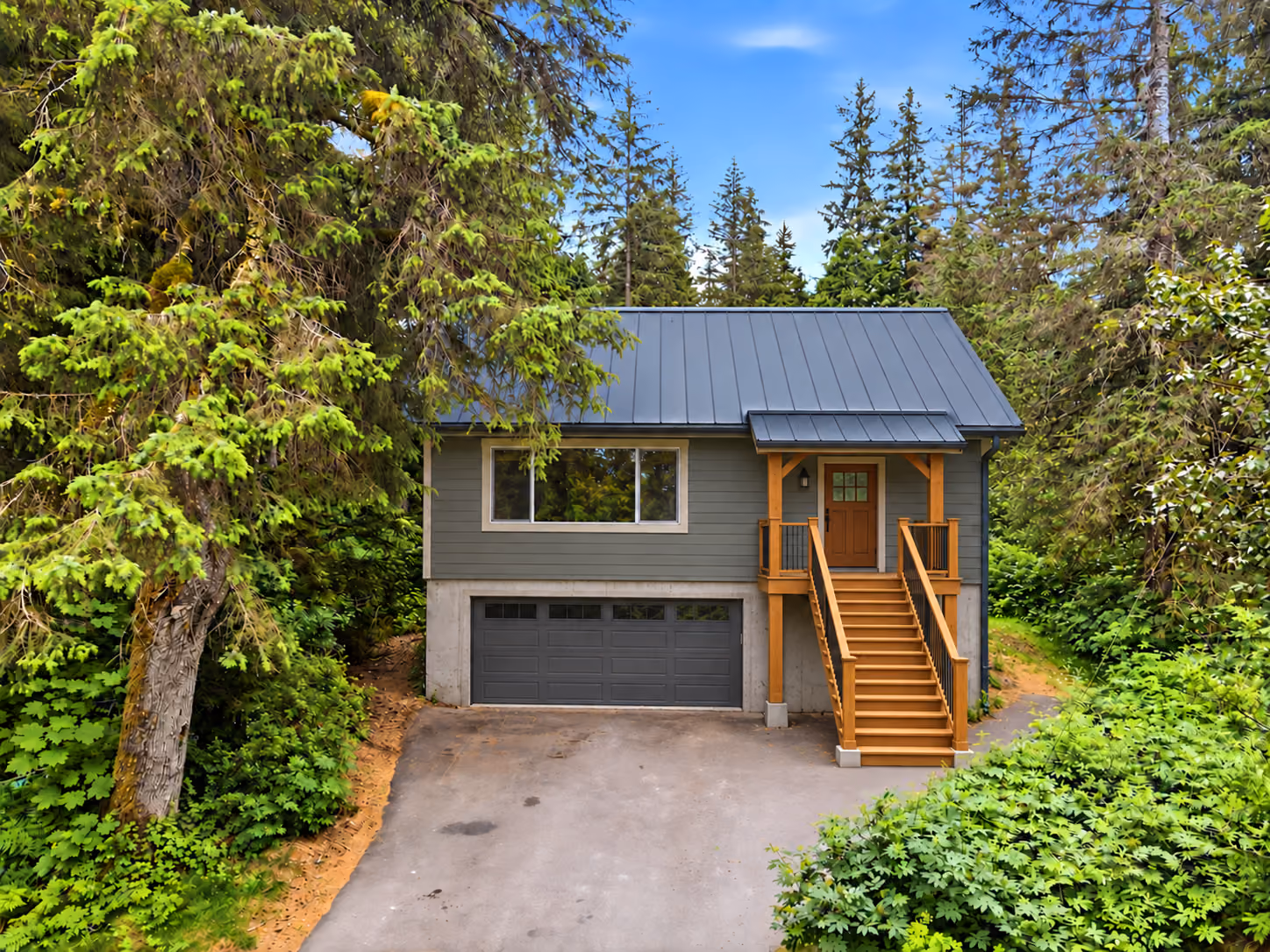 Girdwood home with a dark standing seam metal roof among tall spruce