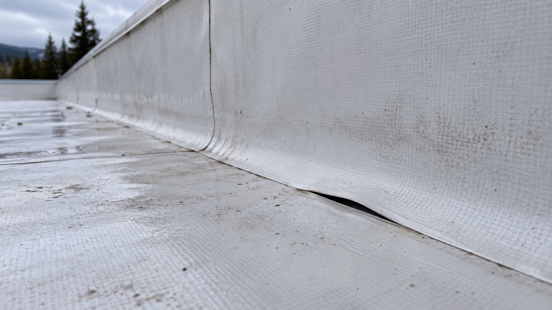 Open seam where the membrane has pulled away at the base of a parapet on a flat roof